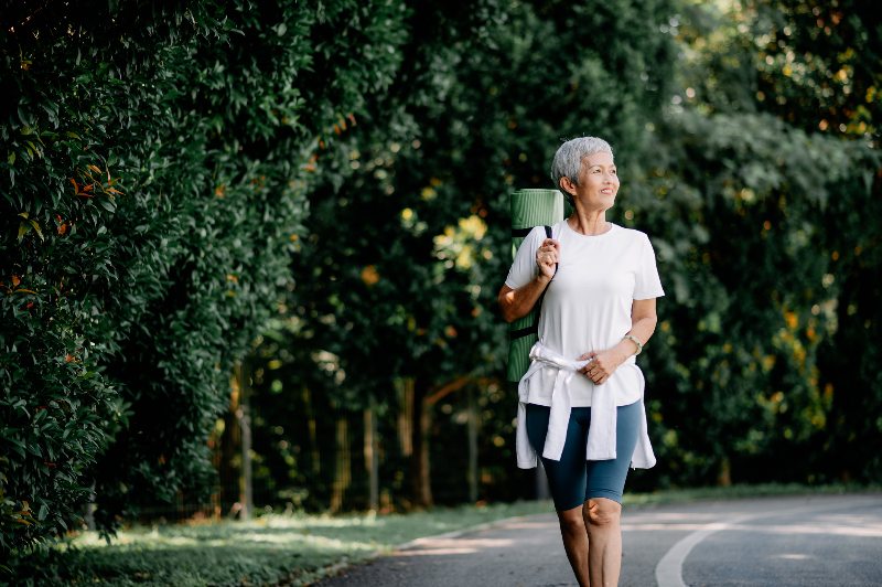 Woman walking and holding a yoga mat by Arizona Vein & Laser Institute